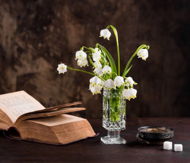 Still life with a bouquet of flowers and a book clipart