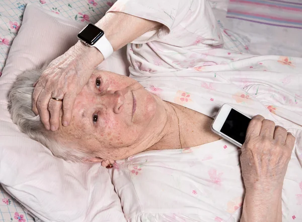 Old woman with smartwatch and smartphone — Stock Photo, Image