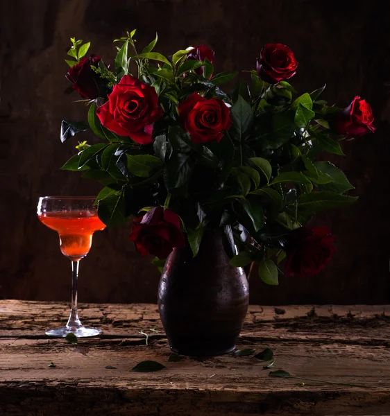 Beautiful red roses in  vase and glass of wine — Stock Photo, Image