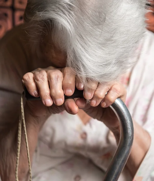 Old woman sitting with a cane — Stock Photo, Image