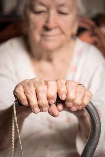 Gammal kvinna sitter med käpp — Stockfoto