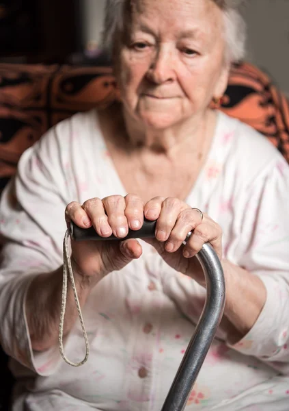 Oude vrouw zitten met een stok — Stockfoto