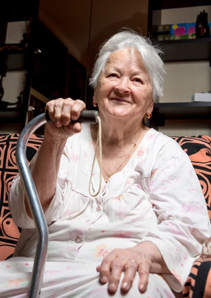 Alte Frau sitzt mit einem Stock — Stockfoto