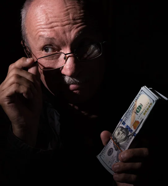 Sly homem sênior segurando notas de dólar — Fotografia de Stock