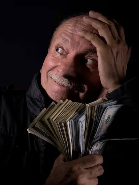 Sly senior man holding dollar bills — Stock Photo, Image