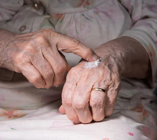 Alte Frau trägt Handcreme auf — Stockfoto