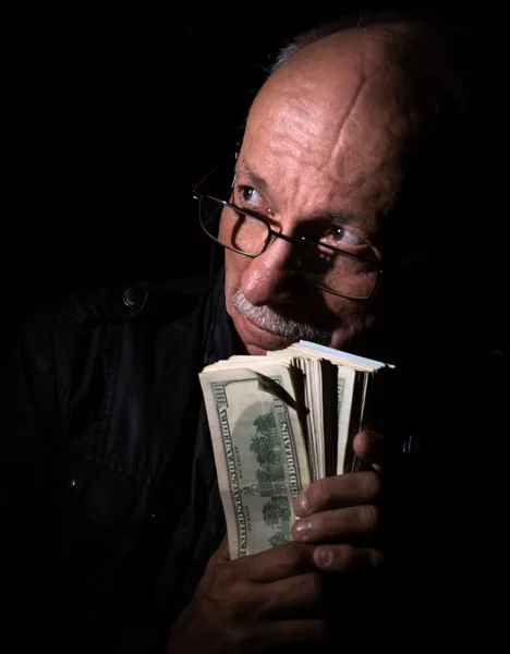 Hombre mayor astuto sosteniendo billetes de dólar —  Fotos de Stock