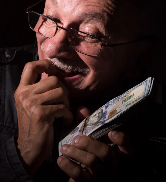 Sly starší muž, který držel dolarové bankovky — Stock fotografie