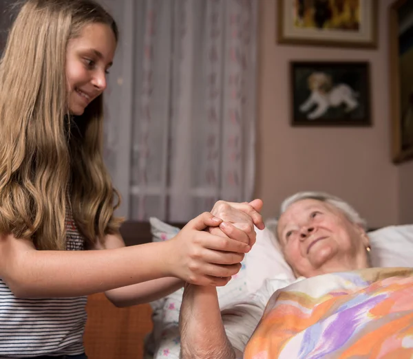 Ragazza premurosa che tiene le mani della vecchia signora — Foto Stock