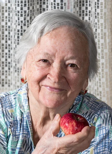Smiling old woman holding red apple — Stock Photo, Image