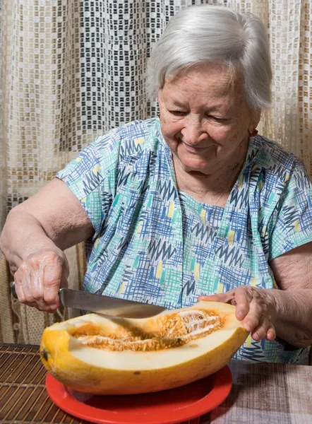 年配の女性は黄色のメロンを食べて — ストック写真