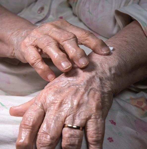 Stara kobieta, stosując krem do rąk — Zdjęcie stockowe