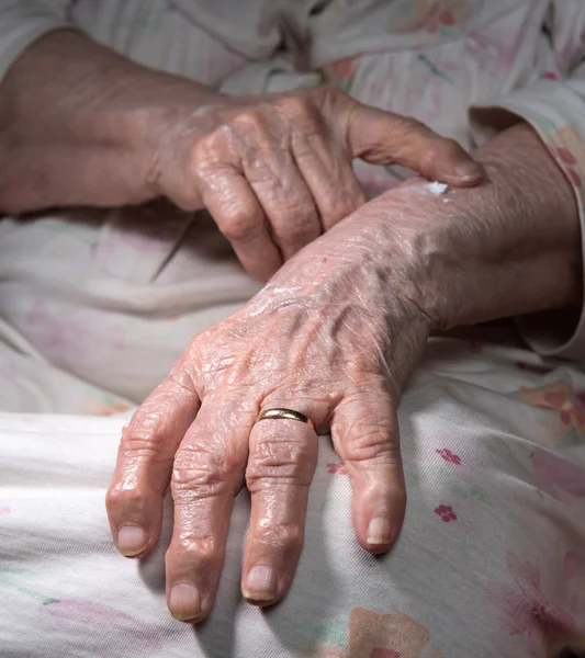 Mujer vieja aplicando crema de manos — Foto de Stock