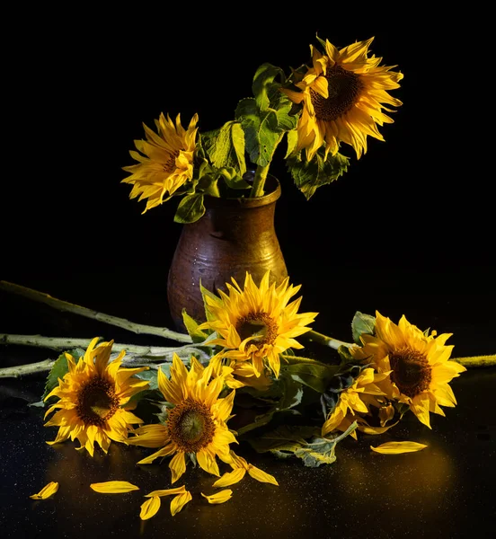 Beautiful bouquet of sunflowers in vase on a black table over black background. Autumn still life