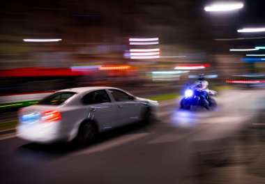 Bir motosikletçi ve hareket hâlindeki bir araba ile tehlikeli şehir trafiği durumu. Odaklanmamış resim