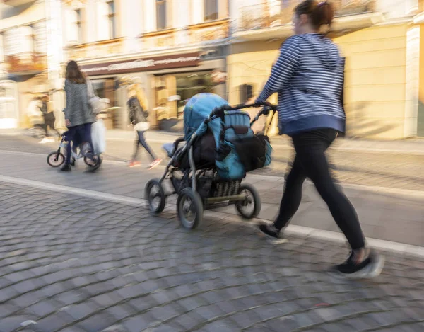 通りを歩いているベビーカーの中に小さな子供を持つ若い母親 意図的な動きのぼかし 専用画像 — ストック写真