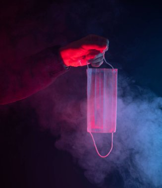 Elinde tıbbi yüz maskesi olan bir adam var.