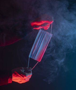 Elinde tıbbi yüz maskesi olan bir adam var.