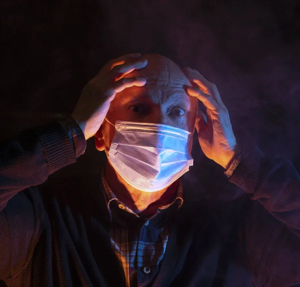 Covid-19 and healthcare concept. Shocked senior man in medical face mask posing smoky dark background