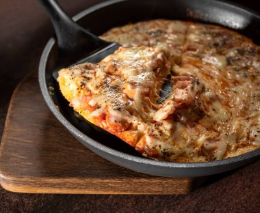 Domatesli ev yapımı pizza, ahşap bir masada mozzarella ve jambon.