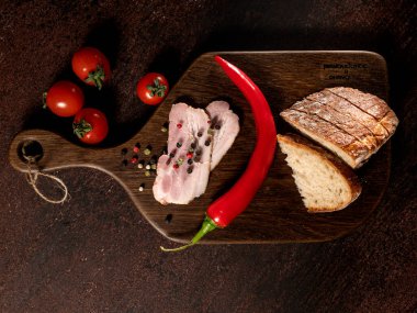 Pastırma dilimleri, ekmek, domates, biber masanın üzerinde tahtada 