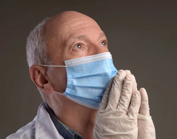 Healthcare and medical concept. Senior medical doctor in protective gloves and face mask over grey background