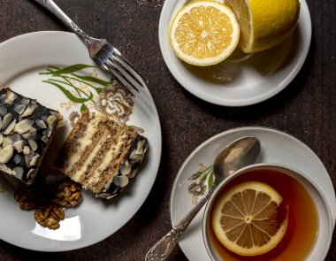 Tatlı kek ve bir fincan sıcak çay. Tahta bir masada limonlu.