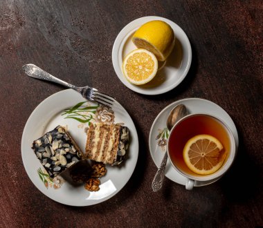 Tatlı kek ve bir fincan sıcak çay. Tahta bir masada limonlu.