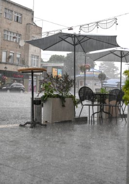 Uzhhorod, Ukrayna - 22 Temmuz 2021: Uzhhorod, Ukrayna 'da yağmurdan ıslanmış bir sokak kafesinin masa ve sandalyeleri