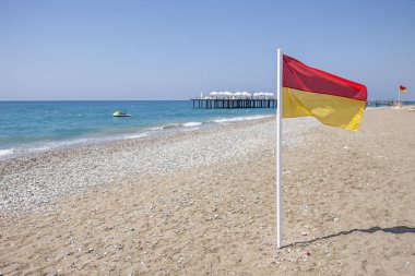 Kumsalda sarı-kırmızı cankurtaran bayrağı