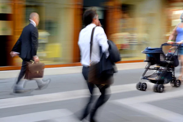Mensen uit het bedrijfsleven en de vrouw met de kinderwagen in de straat — Stockfoto
