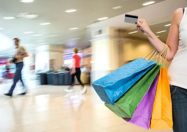 Woman holding credit card and shopping bags — Stock Photo, Image