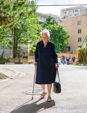 yaşlı kadın bastonla yürüyor