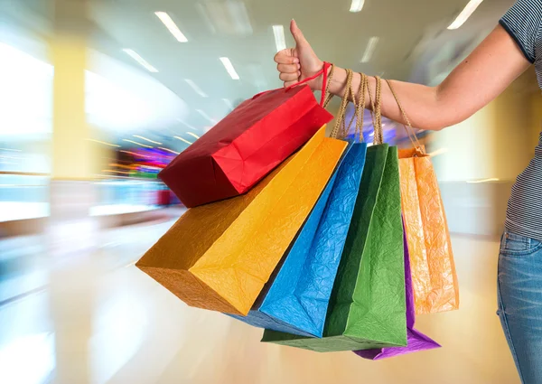 Mulher mostrando polegar para cima e segurando sacos de compras — Fotografia de Stock