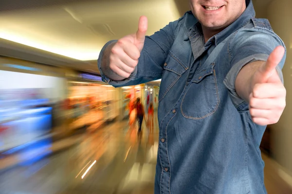 Jovem gesticulando polegares no shopping — Fotografia de Stock