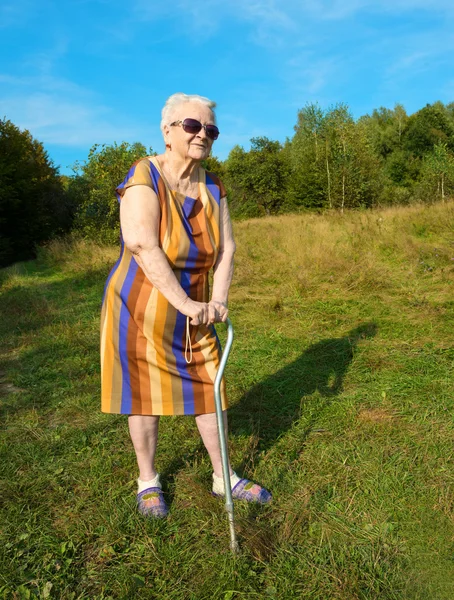 Gammal kvinna poserar med käpp — Stockfoto