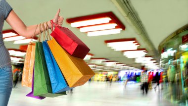 alışveriş torbaları basılı tutup ok işaret gösteren kadın