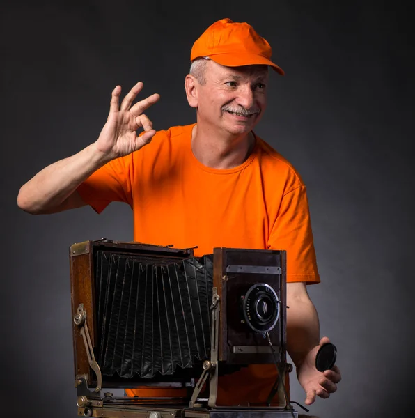 Uśmiechający się starszy człowiek z aparatu vintage zdjęcie drewniana — Zdjęcie stockowe
