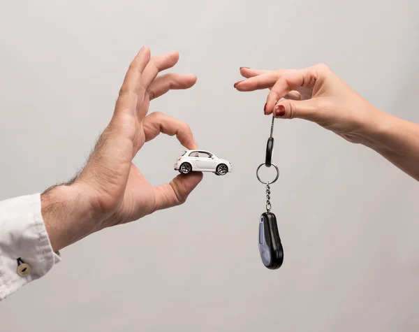 Homem segurando carro pequeno, mulher segurando chave do carro — Fotografia de Stock