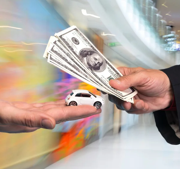 Homem segurando carro pequeno, outro homem segurando notas de dólar — Fotografia de Stock