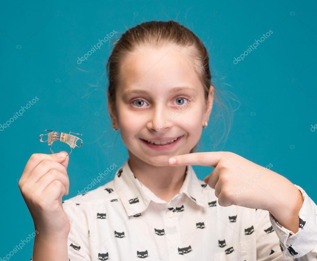 Happy girl holding dental braces 