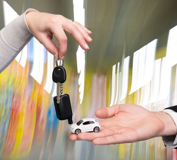 Hombre sosteniendo coche pequeño, mujer sosteniendo la llave del coche — Foto de Stock