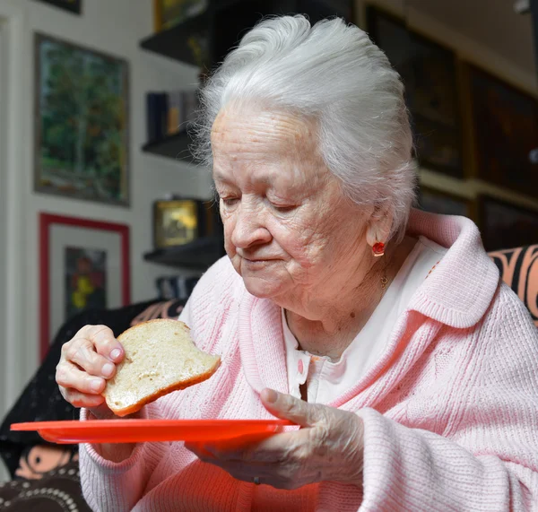 Oude vrouw een sneetje brood eten — Stockfoto