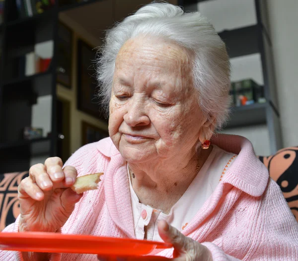 Vieille femme mangeant une tranche de pain — Photo