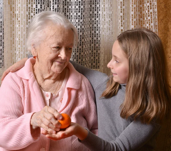 Девушка дарит мандаринские апельсины своей бабушке — стоковое фото