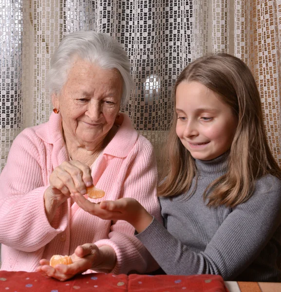 Menina dando laranjas mandarim para sua avó — Fotografia de Stock