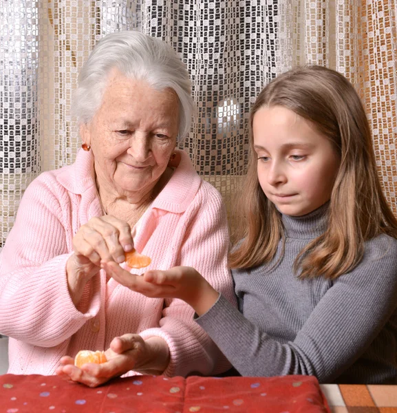 Mädchen schenkt seiner Großmutter Mandarinen — Stockfoto