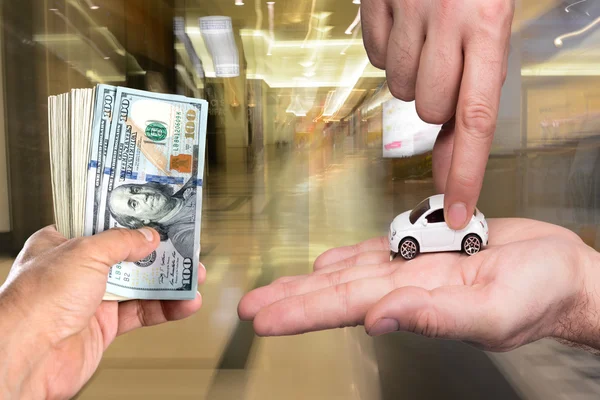 一男子手持美元钞票，另一名男子拿着小型车 — 图库照片
