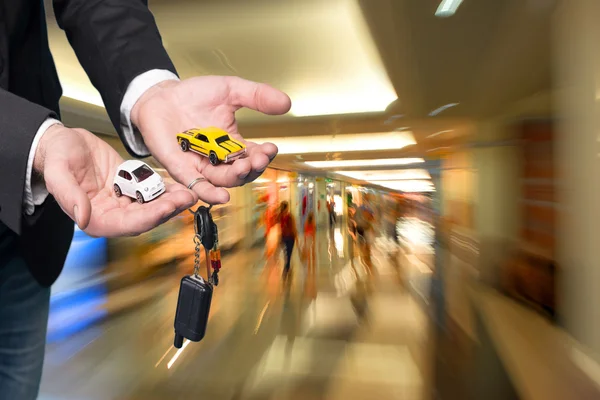 Hombre de negocios en traje negro sosteniendo modelos de coche pequeño — Foto de Stock