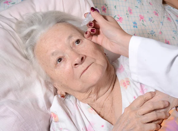 Krankenschwester träufelt Augentropfen auf alte Frau — Stockfoto